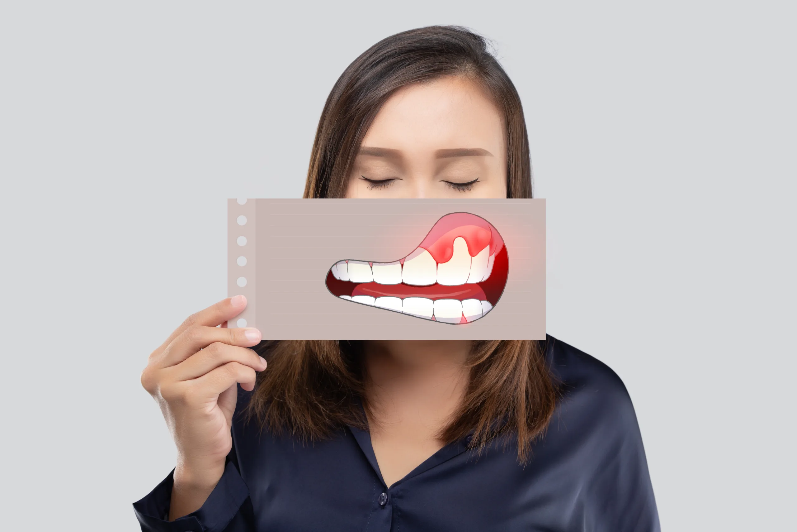 asian woman dark blue shirt holding paper with periodontal gingivitis cartoon picture his mouth against gray background scaled