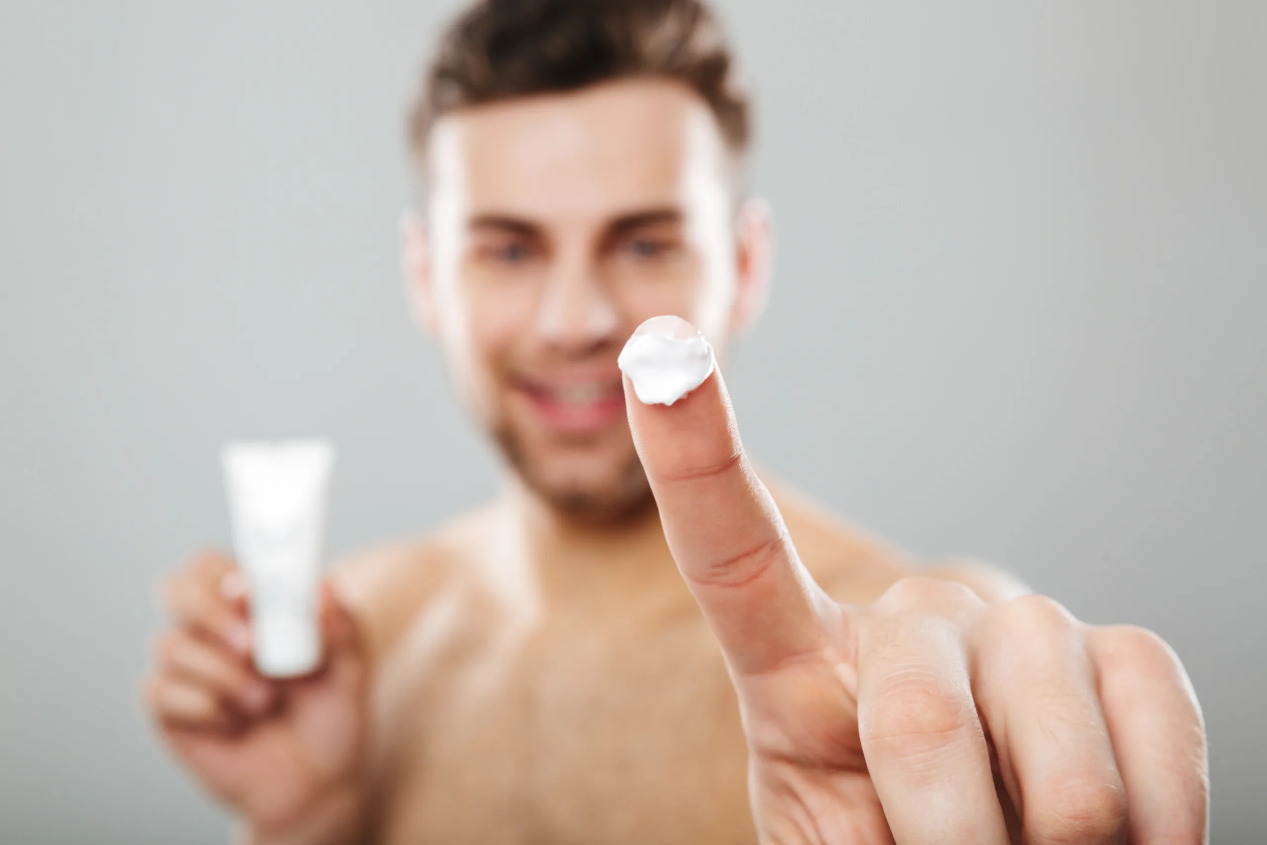 beauty portrait half naked man applying face cream scaled