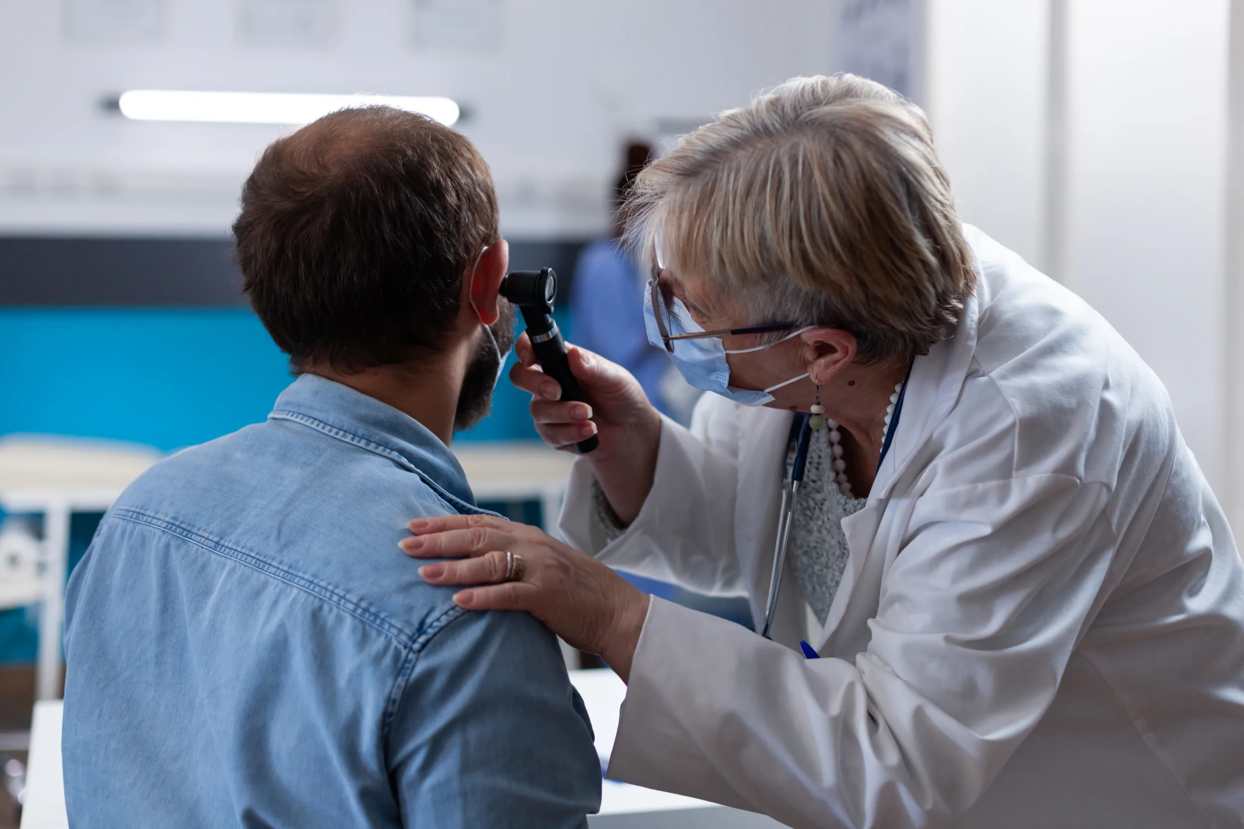 close up physician using otoscope ear consultation with patient woman otologist checking infection with otolaryngology instrument medical visit coronavirus pandemic scaled