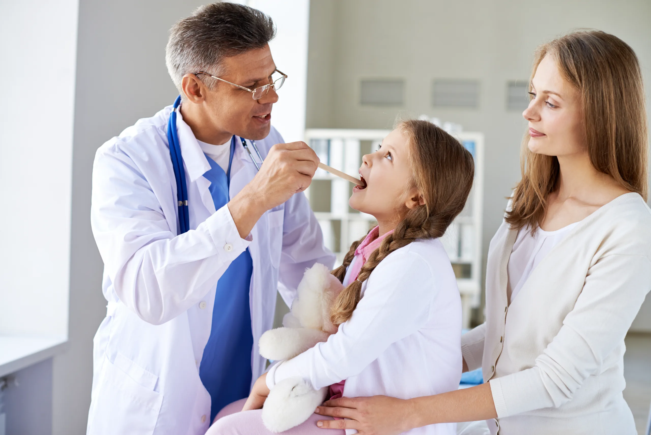 doctor examining little girl with her mother medical office scaled
