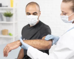 female physiotherapist with medical mask checking man s elbow