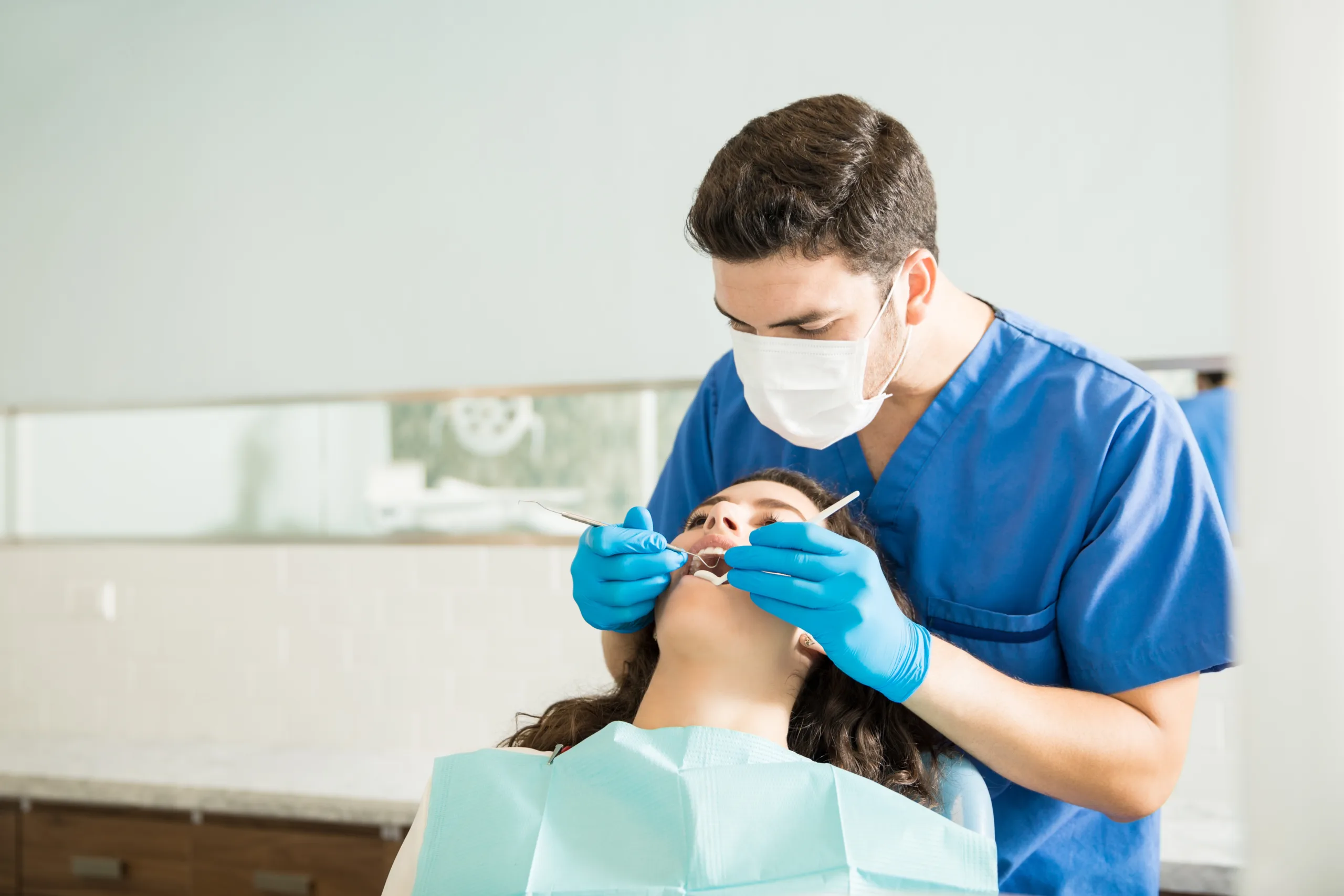 male dentist examining young woman with dental carver medical clinic scaled