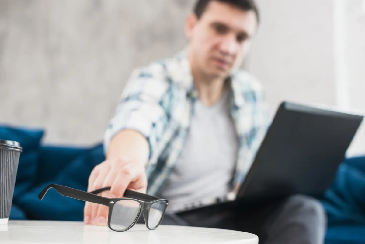 male with laptop put down glasses table