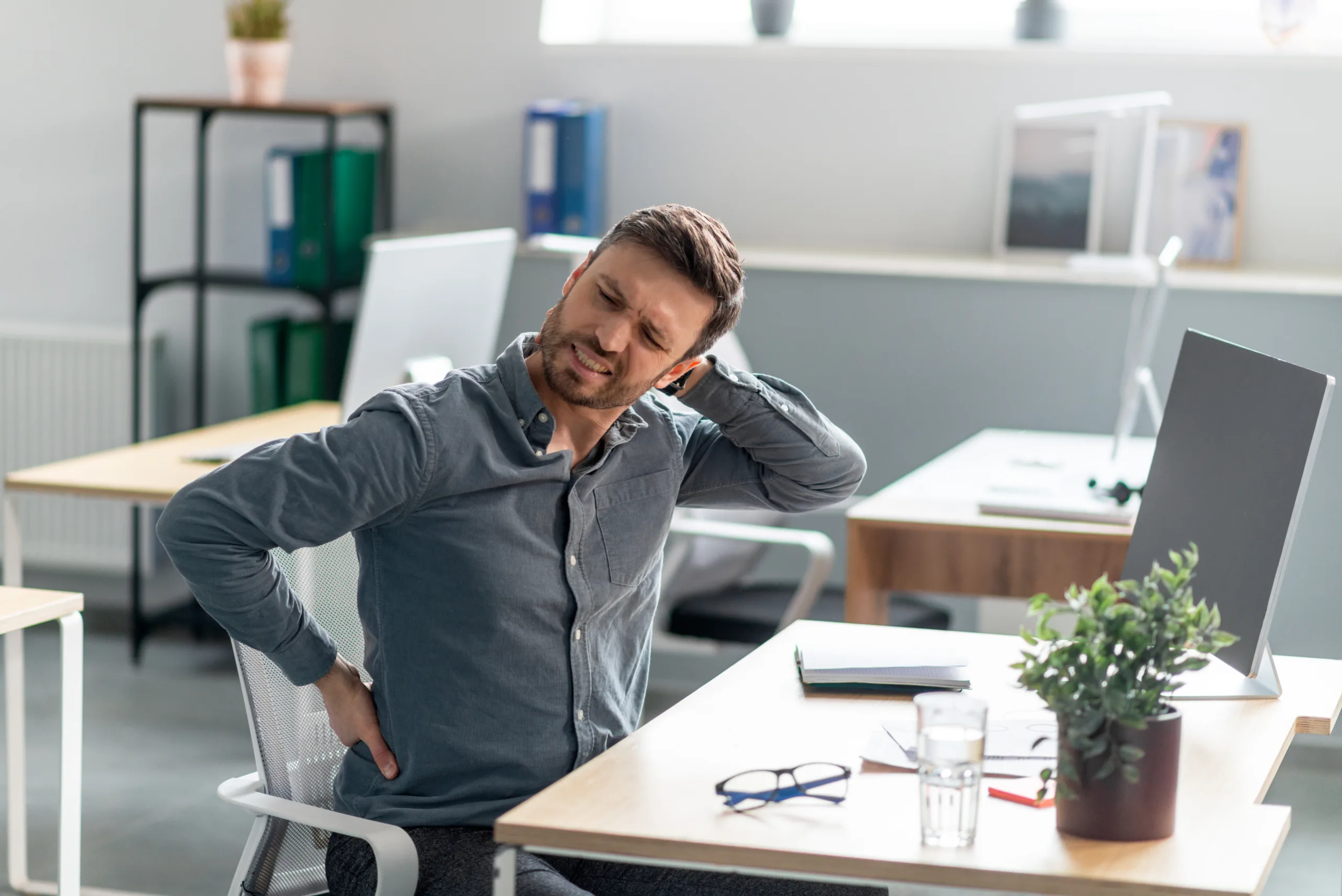 mature businessman massaging aching neck back suffering from pain after computer work sitting scaled