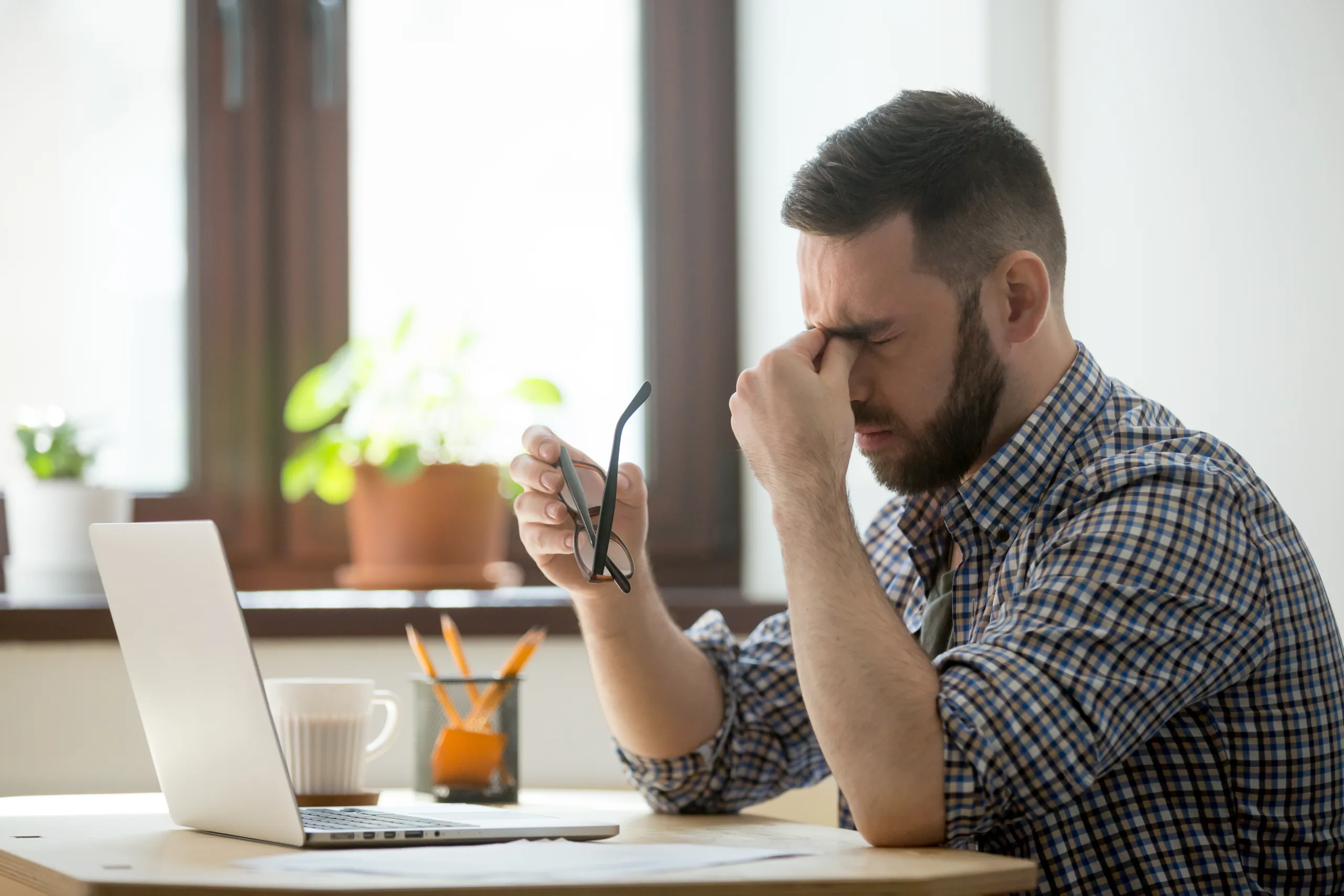 stressed male massaging nose bridge suffering from headache scaled