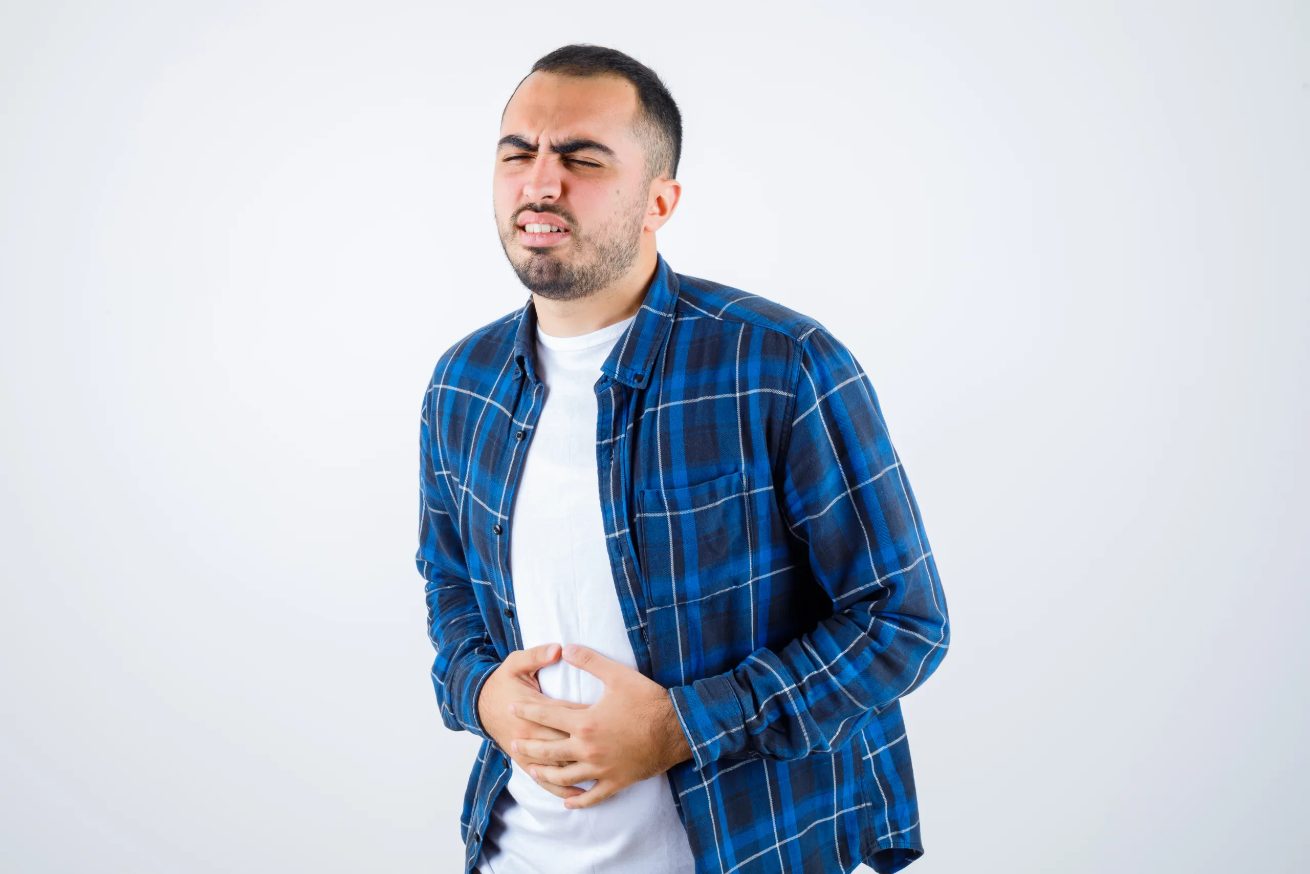 young man having bellyache checked shirt white t shirt looking exhausted scaled