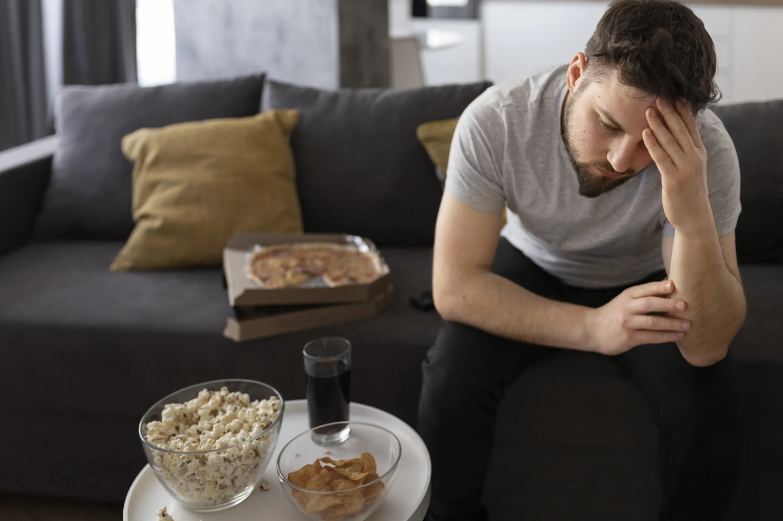 young man tired sofa home sitting junk food scaled