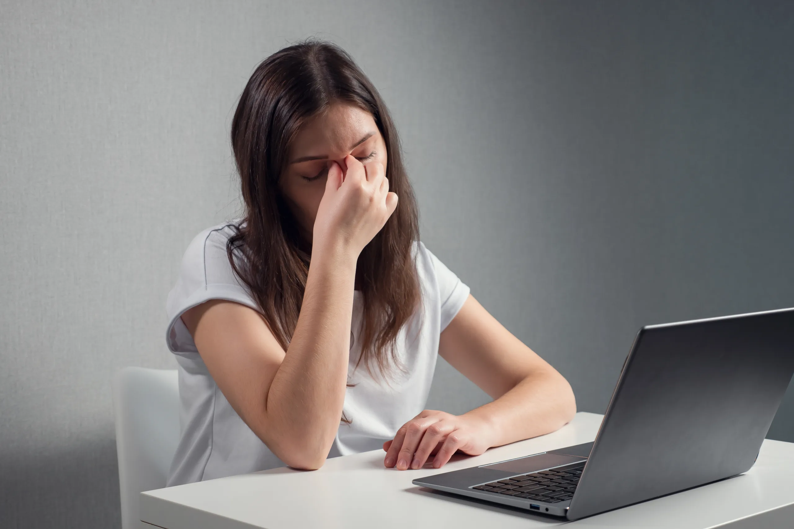 young woman massaging bridge nose eyes while sitting front laptop scaled
