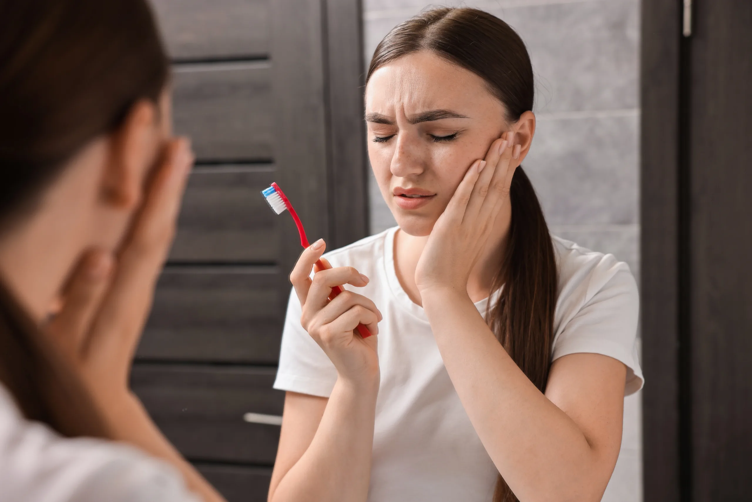 young woman with toothbrush suffering from toothache bathroom scaled